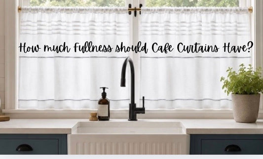 White linen café curtains with soft gathers framing a bright kitchen window above a farmhouse sink, illustrating the ideal fullness for café curtains.